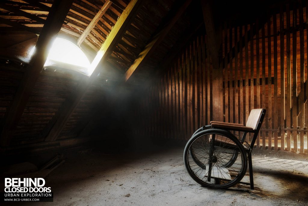 Wheelchair Hospital - Light shines onto wheelchair in the dusty attick